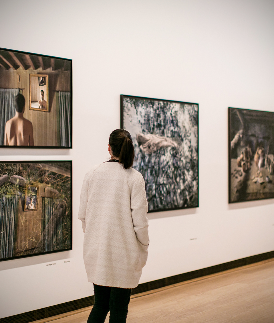 Mujer de espaldas observando cuadros en exposición en crucero del Hospital Real